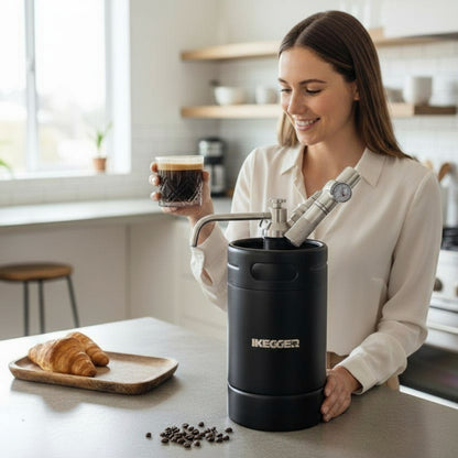 Woman holding a coffee cup next to an IKEGGER nitro coffee maker on a kitchen counter.