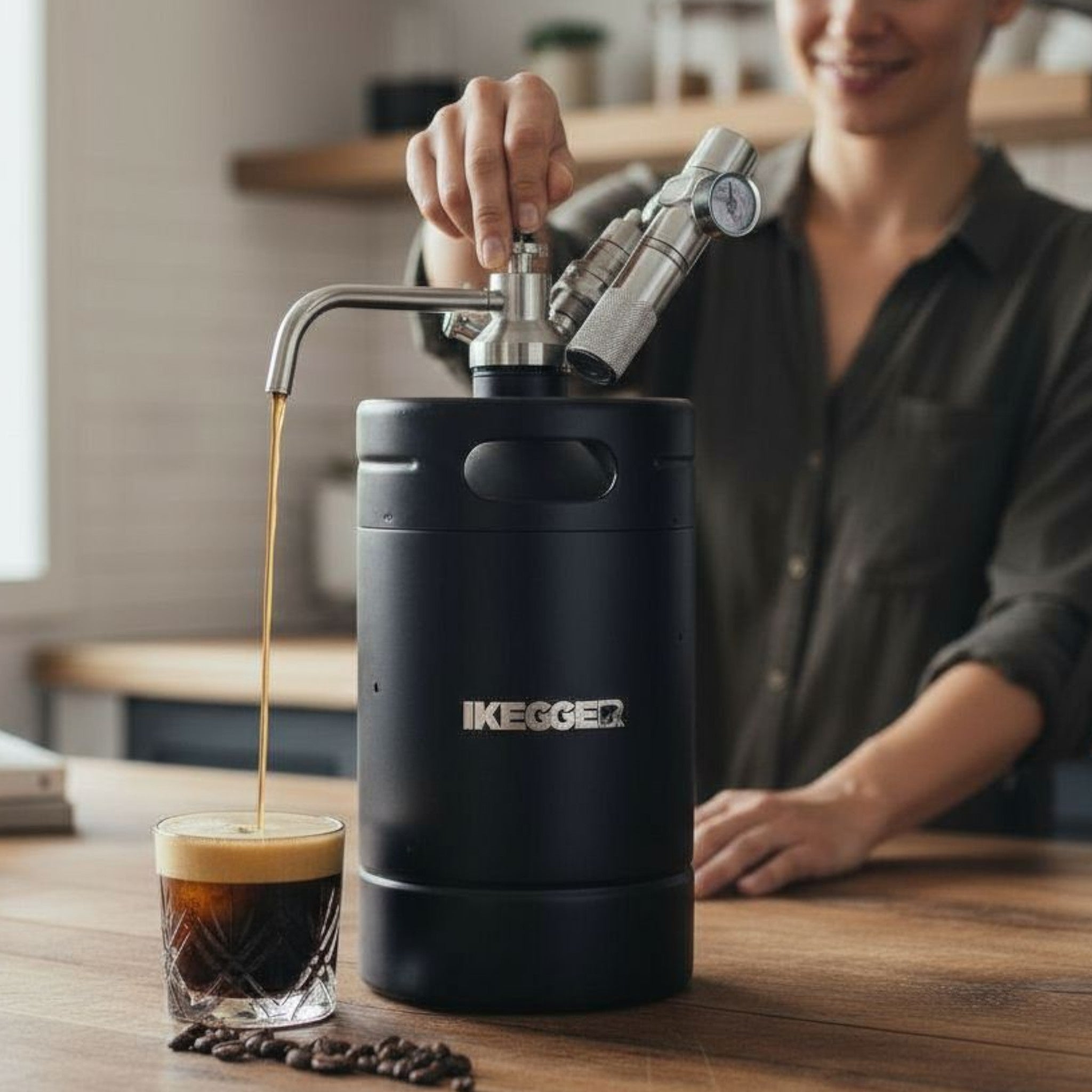 Person using a Kegger coffee keg to pour coffee into a glass on a wooden table.